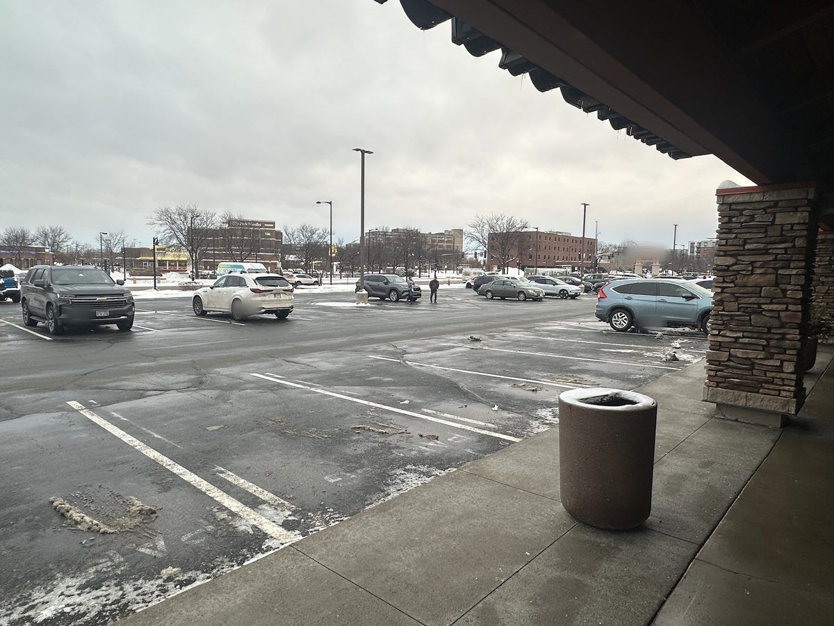 Cleared storefront walkway under an awning next to a plowed parking lot
