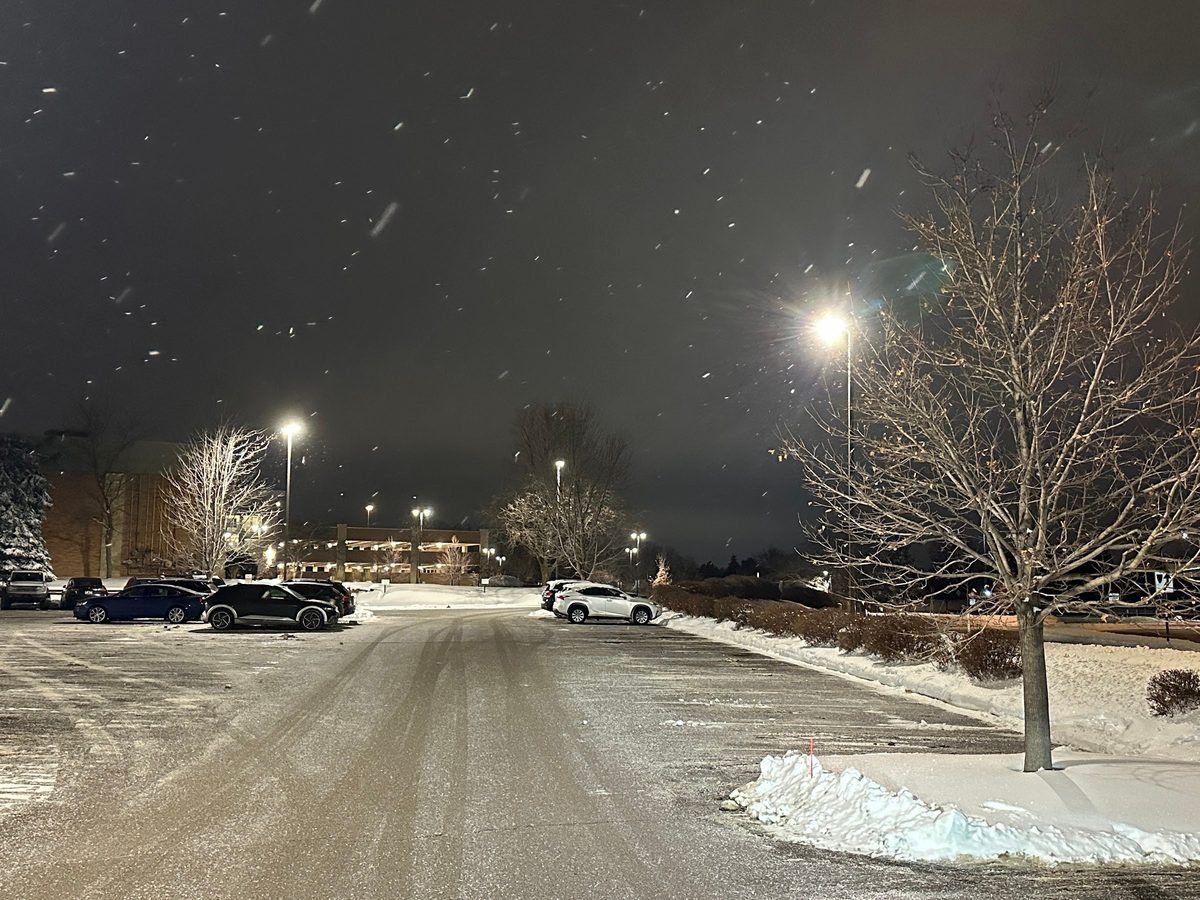 Plowed parking lot under lights during a nighttime snowfall