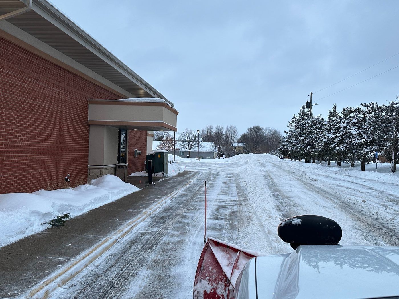 View from a plow truck clearing snow along a brick building wall