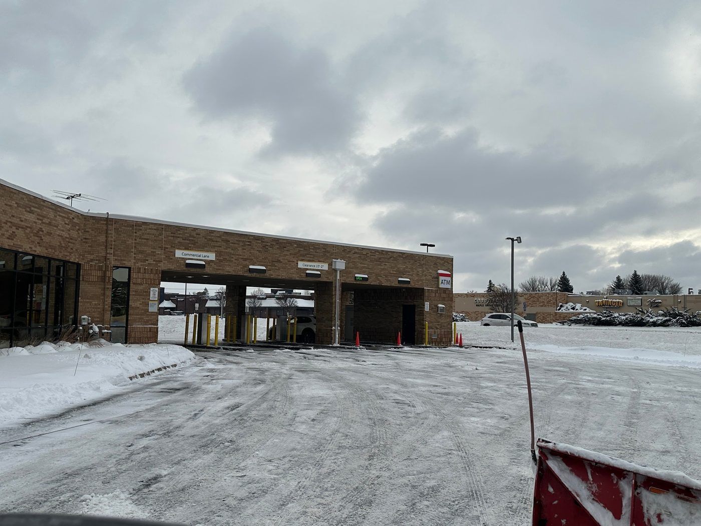 Brick commercial building with covered drive-up bays in a plowed lot