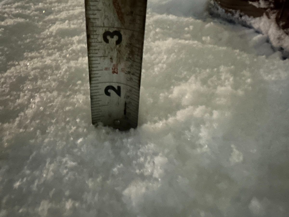 Tape measure standing in fresh snow to check the depth