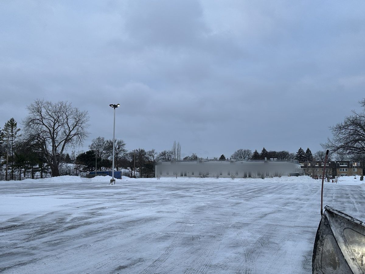 Plow blade at the edge of a large snow covered lot