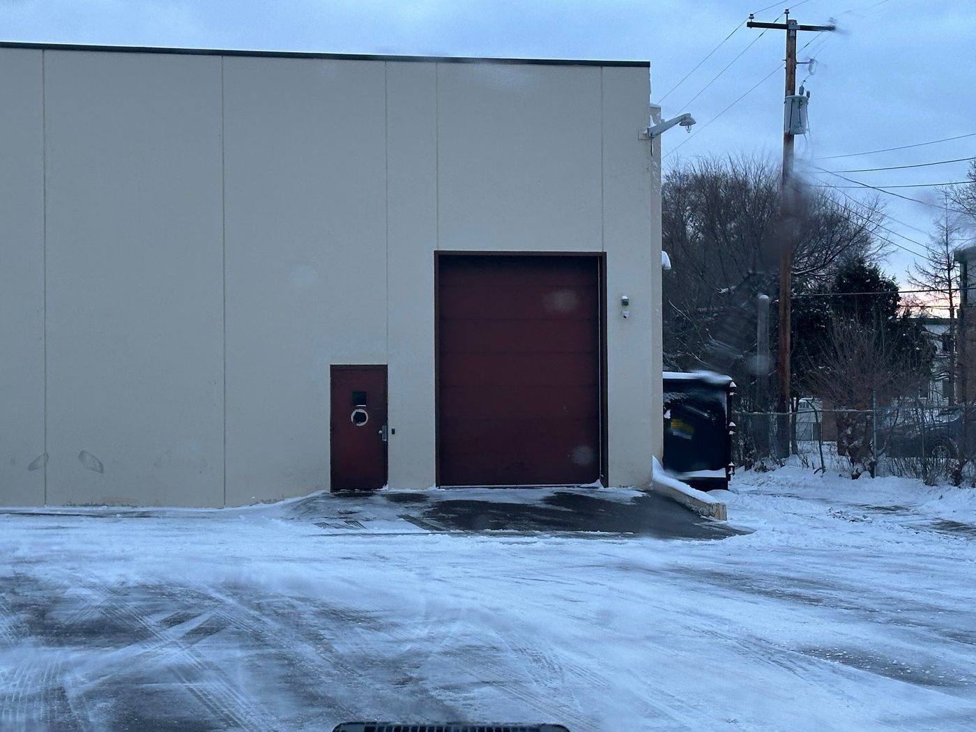 Overhead loading door on a tan building with cleared pavement in front