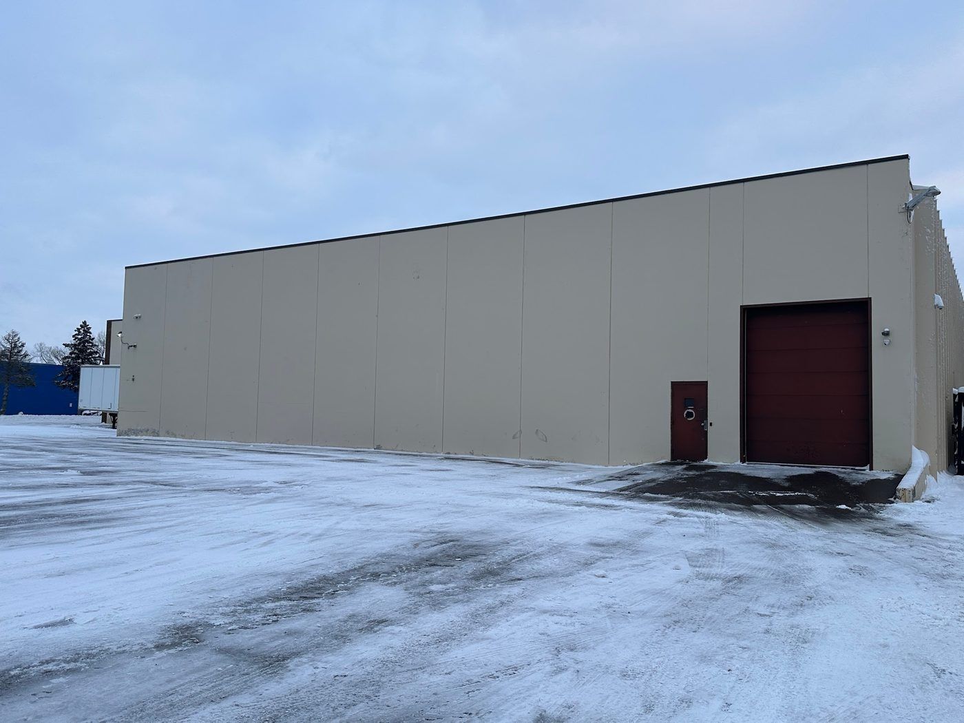 Plowed pavement along the side wall and loading door of a tan building