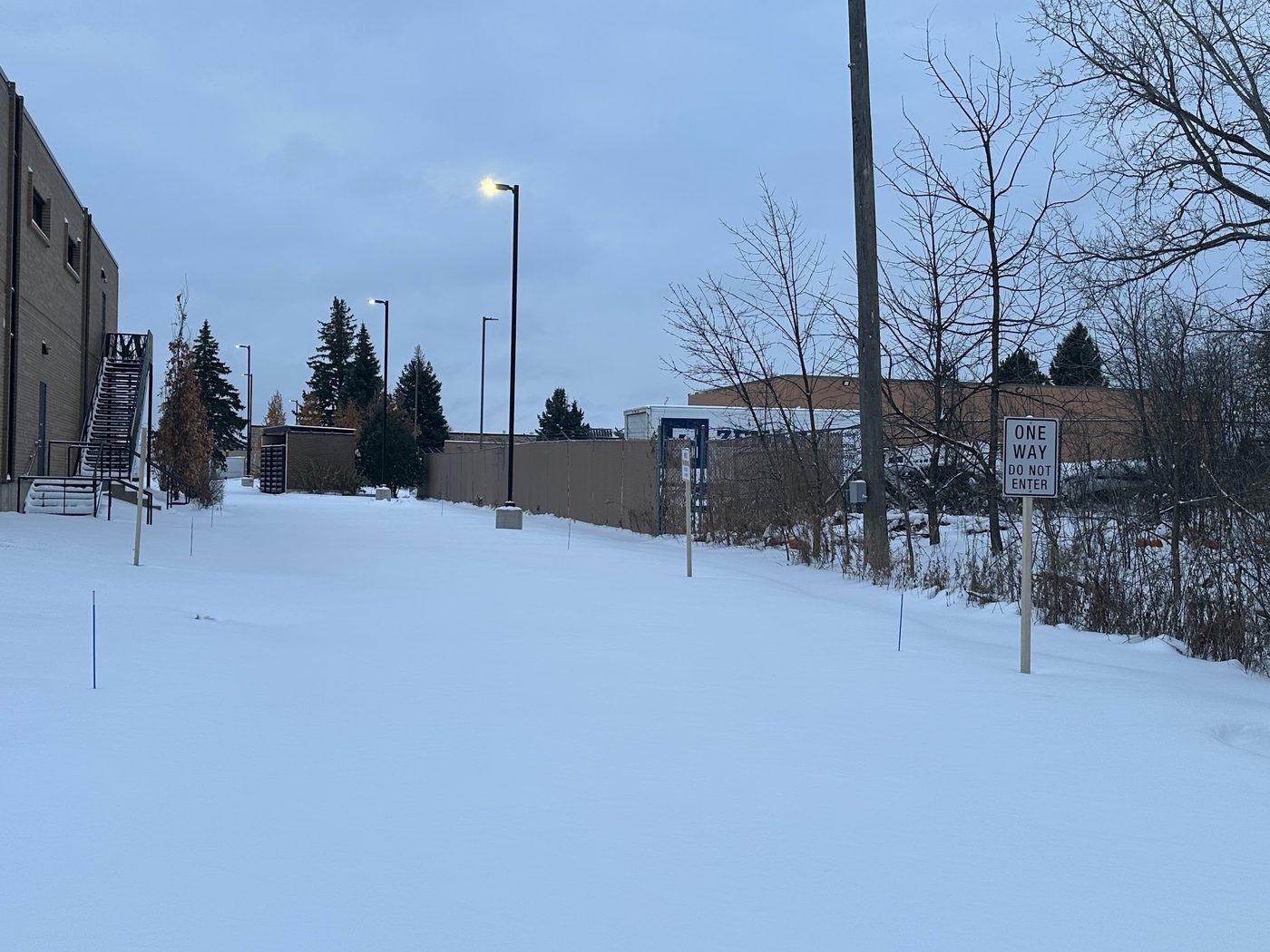 Snow-covered parking lot beside a commercial building before plowing