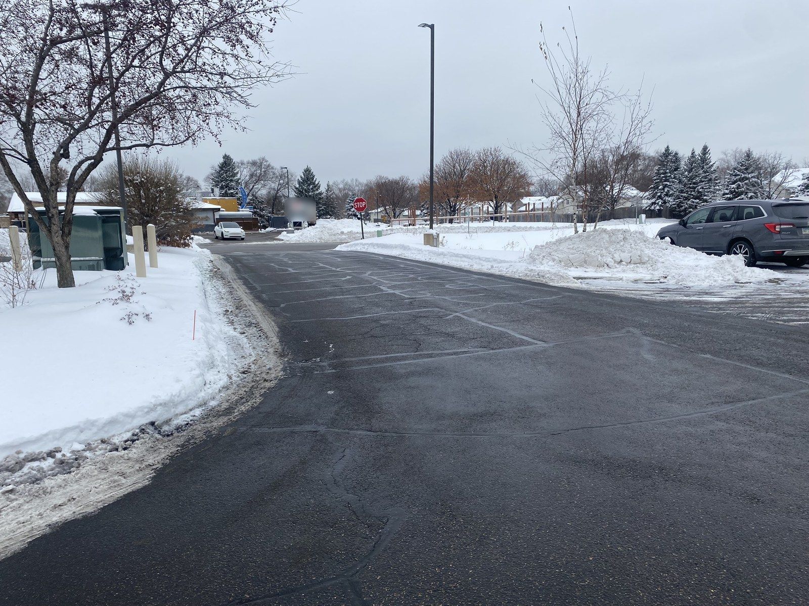 Plowed drive lane with snowbanks along a curb and parked cars
