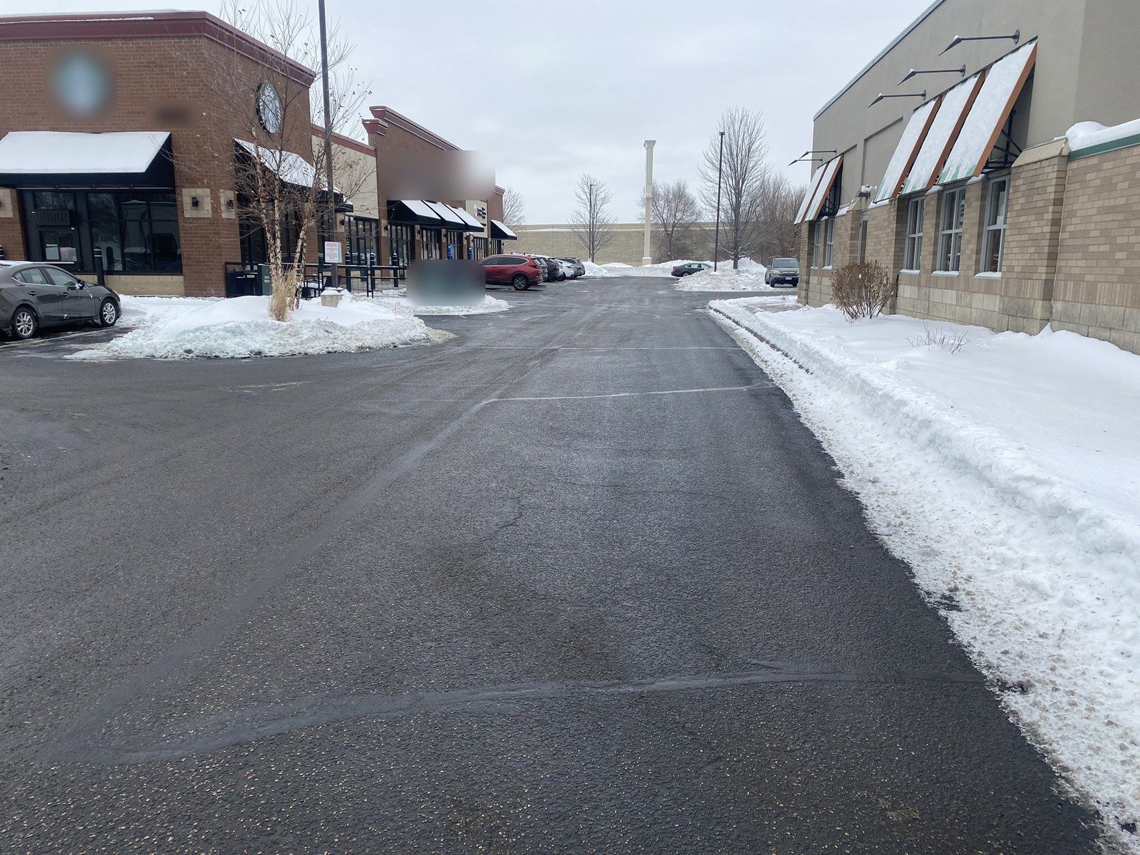 Plowed lane beside a brick retail building, snow banked at its edge