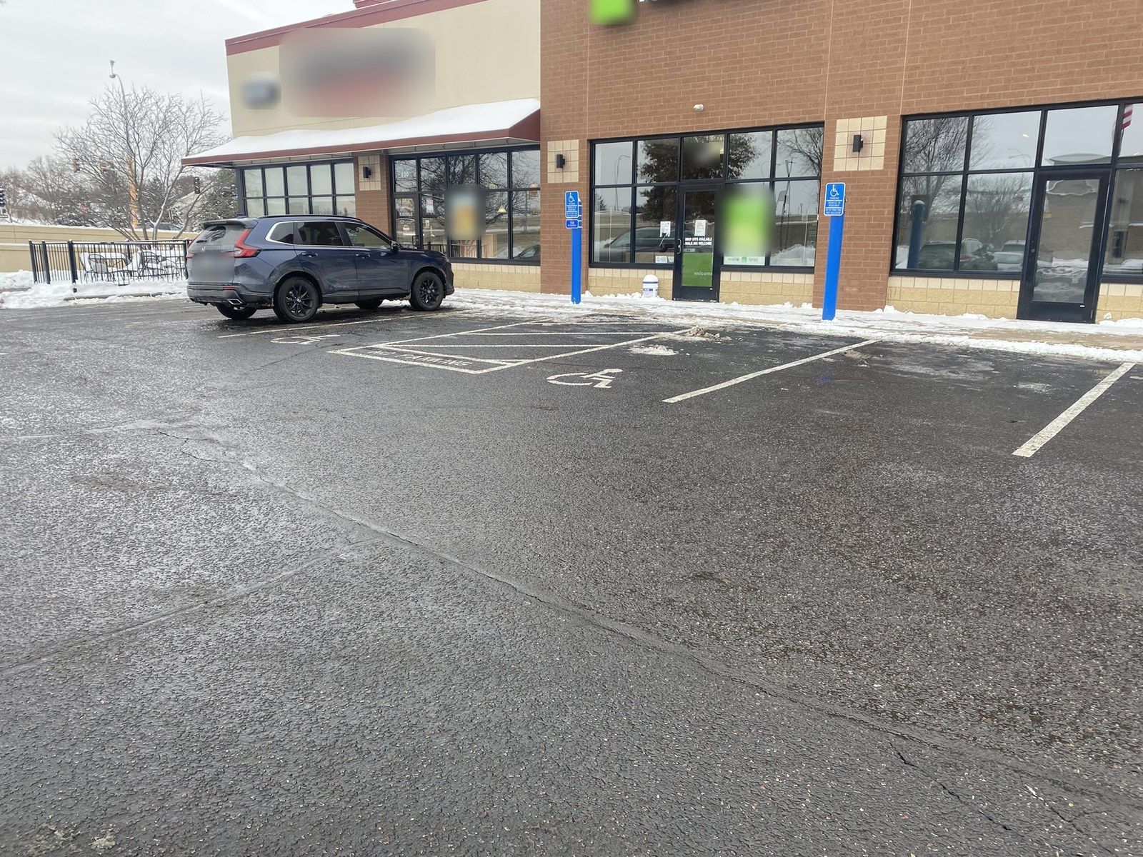 Plowed parking stalls and accessible spaces in front of brick storefronts