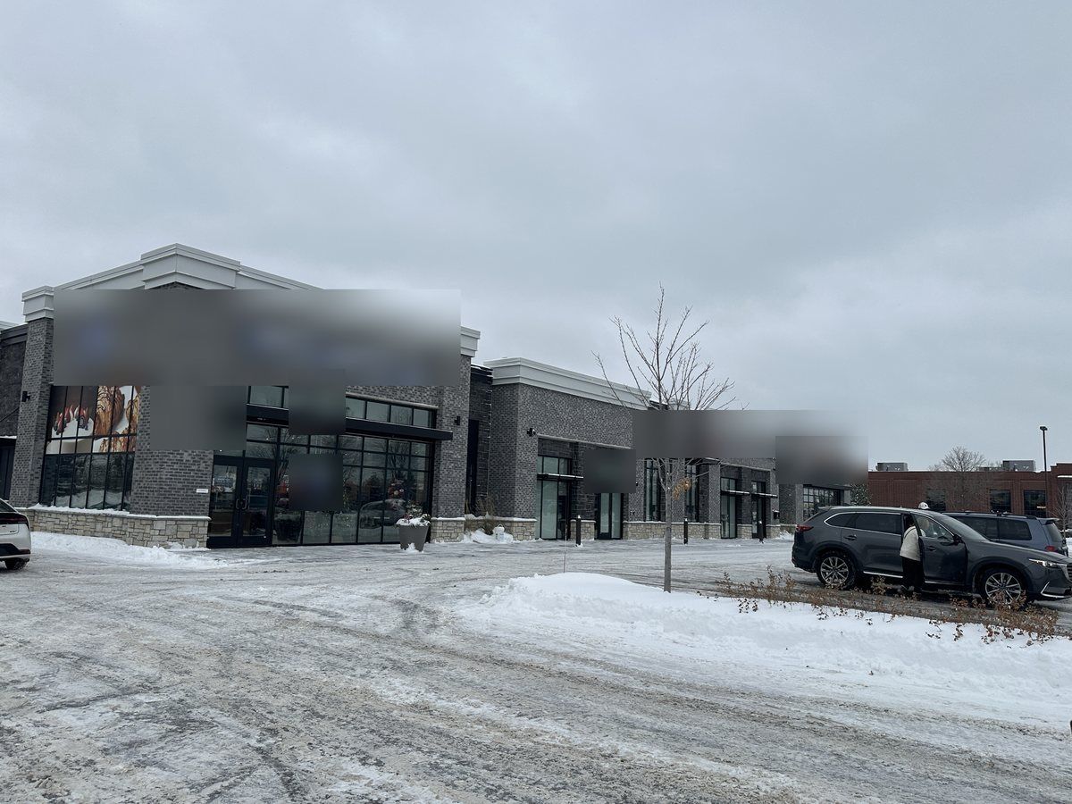 Plowed lot and snowbank in front of a newer retail building