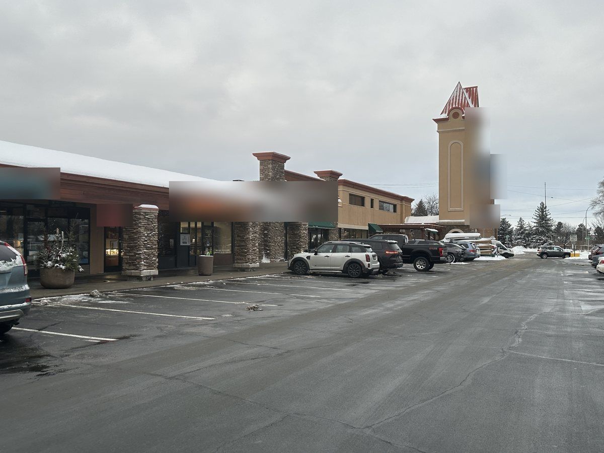 Plowed parking aisle at a shopping center with cars parked by the stores