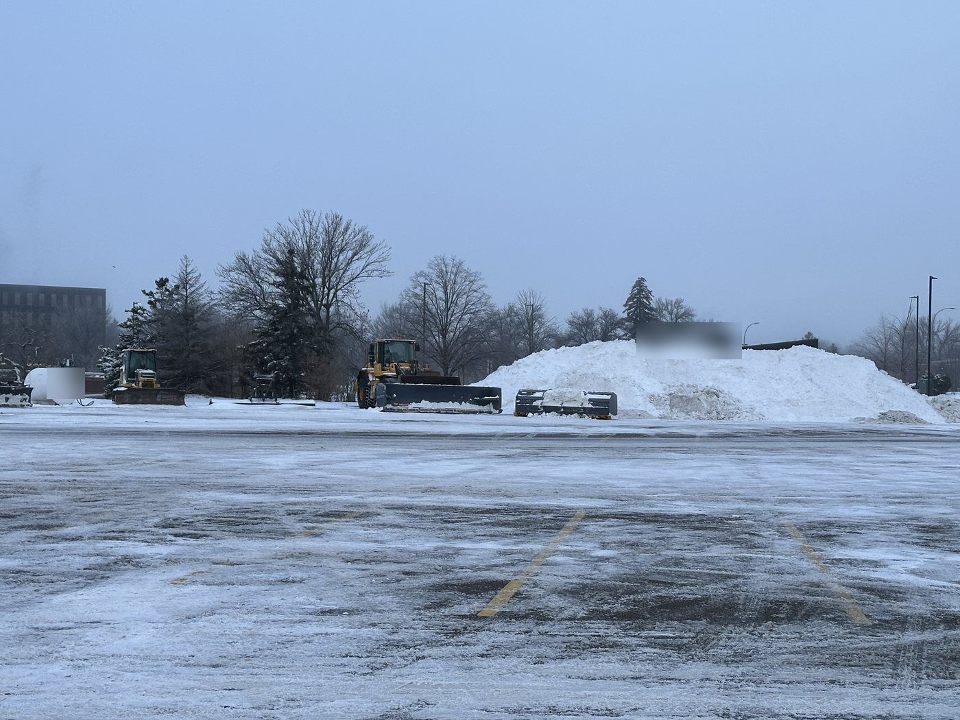 Large mound of plowed snow on the border of a big parking lot