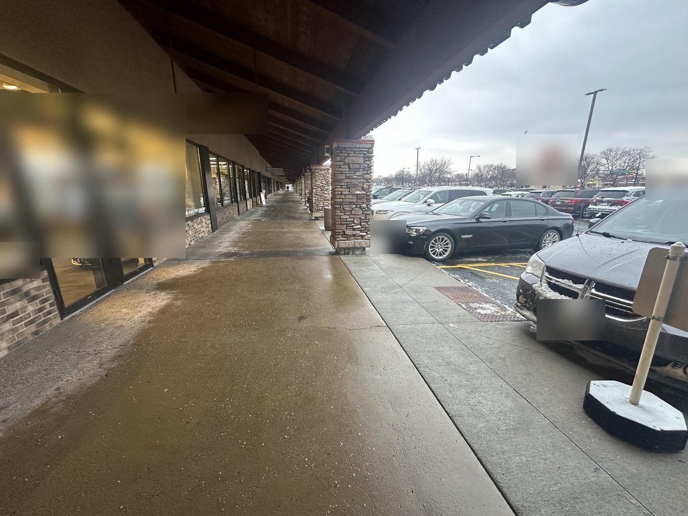 Cleared covered walk running along a row of storefronts beside a parking lot