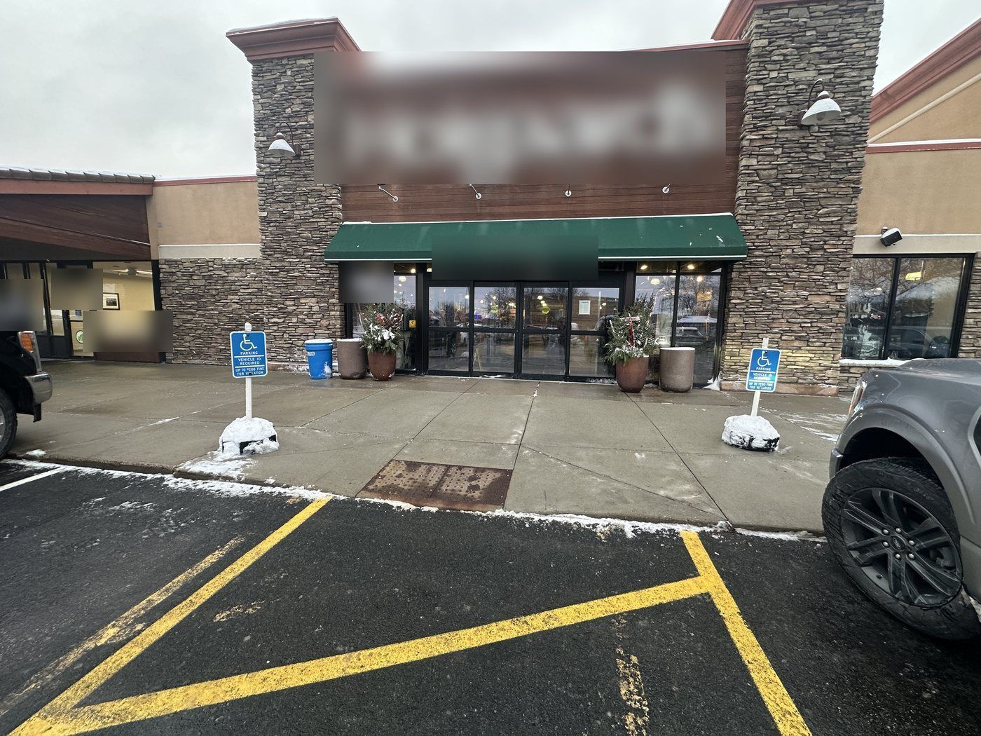 Retail store entrance with two cleared accessible parking stalls and a cleared walk after snow