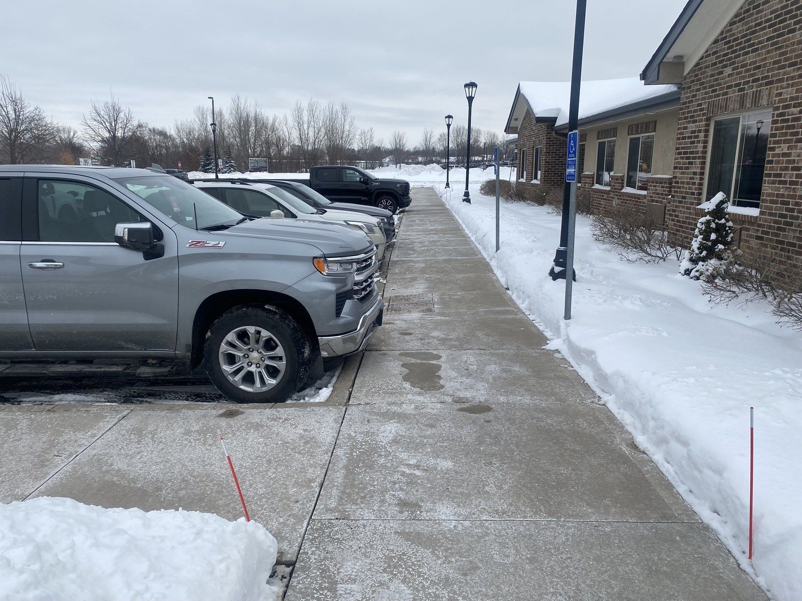 Cleared concrete sidewalk between parked trucks and a brick office building