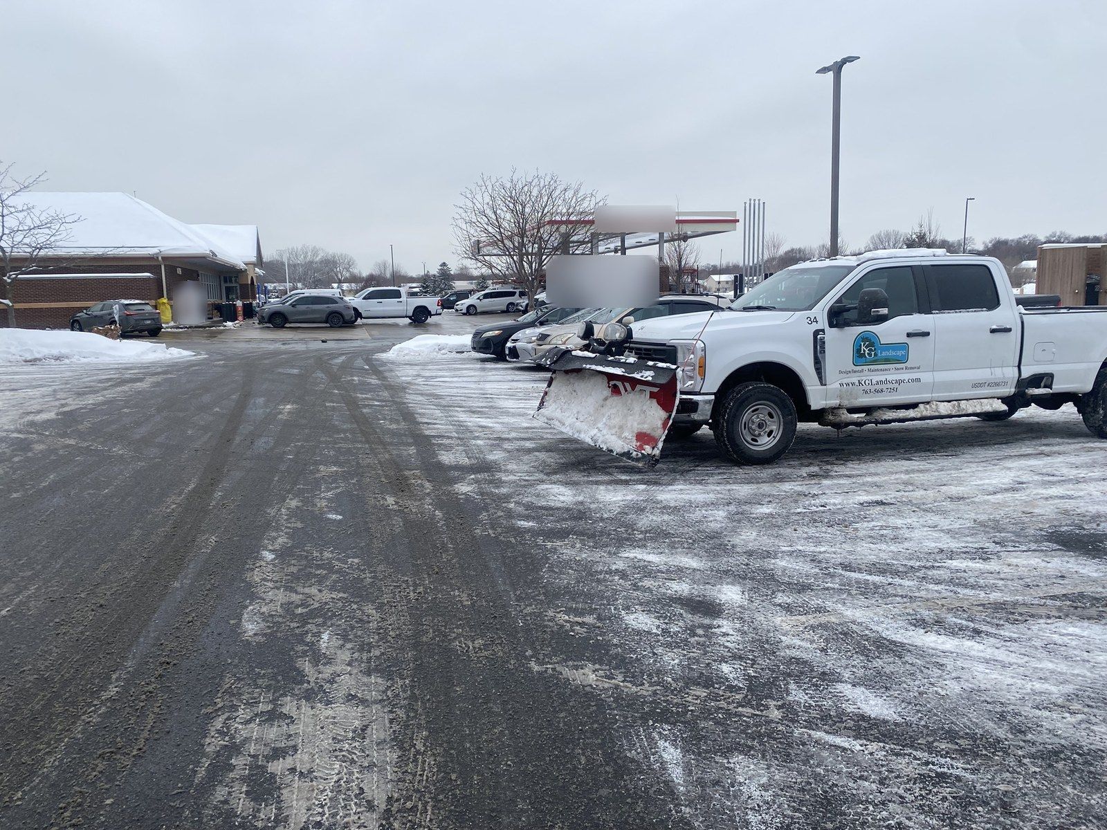 KG Landscape plow truck with its blade down in a cleared retail lot