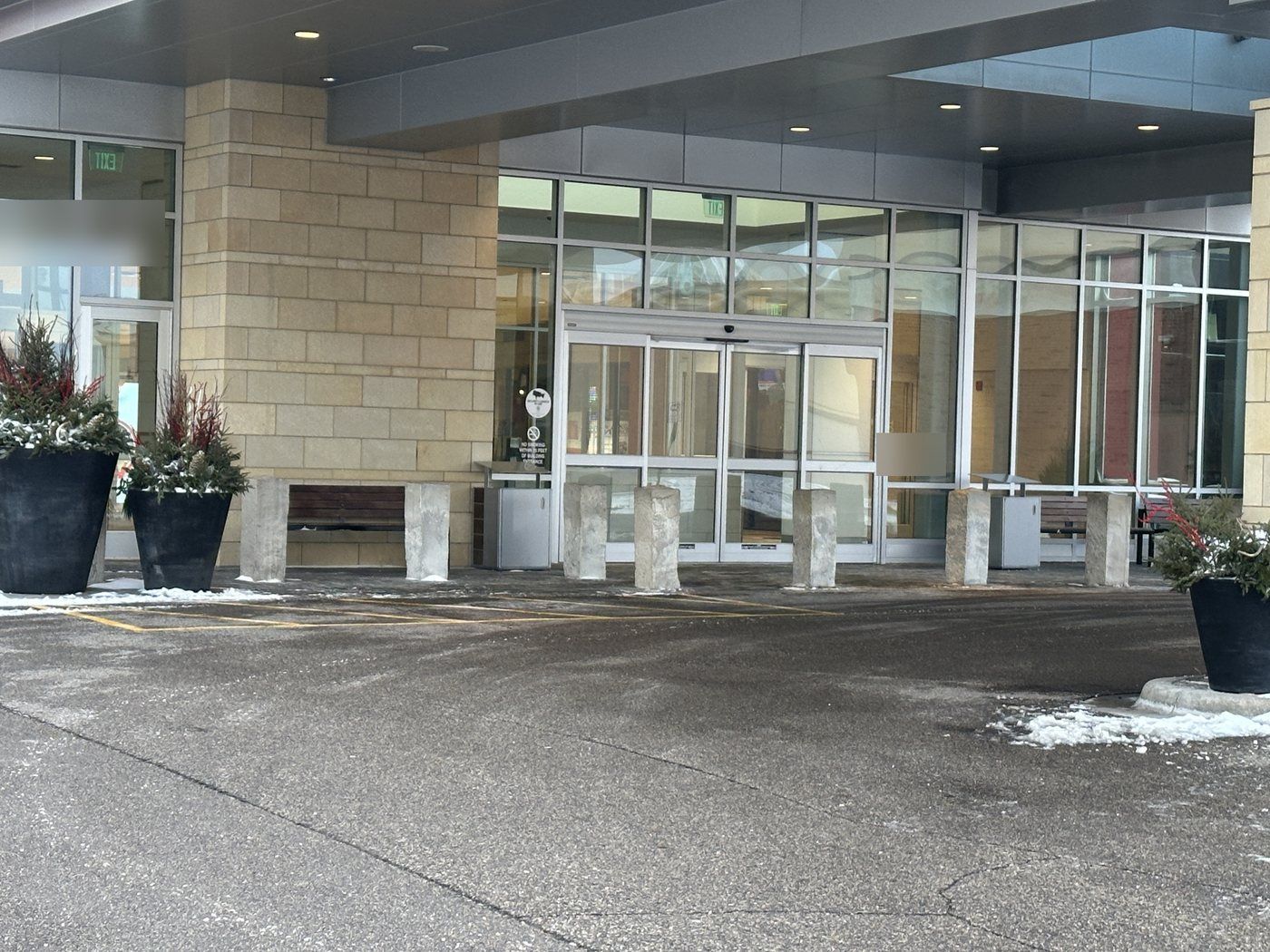 Glass building entrance under a canopy with the drive and walk cleared of snow