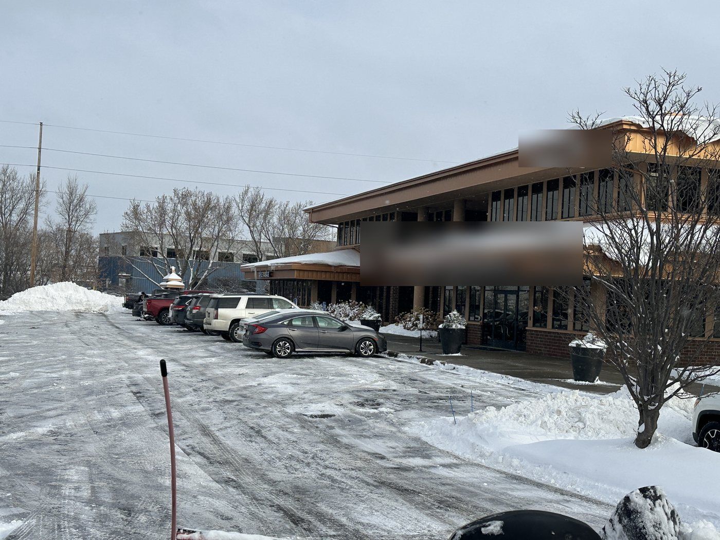 Plowed office parking lot with snow piled at the edge and cars parked