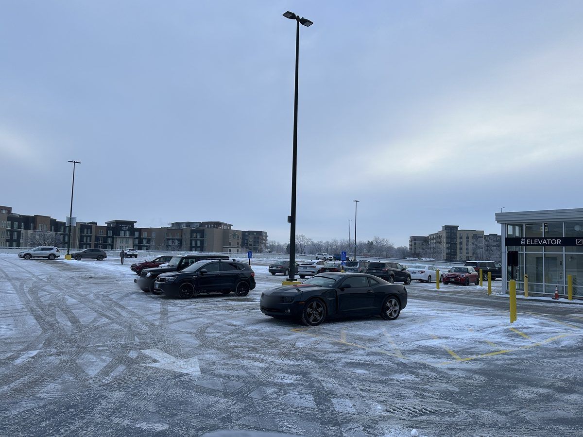 Plowed office lot with cars parked near light poles