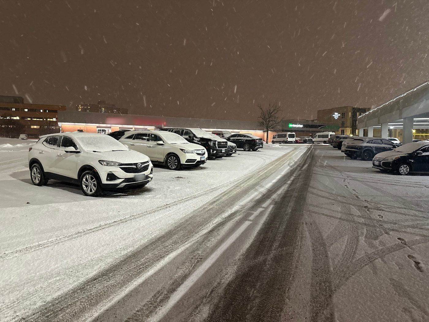 Parking lot under lights at night during a snowfall