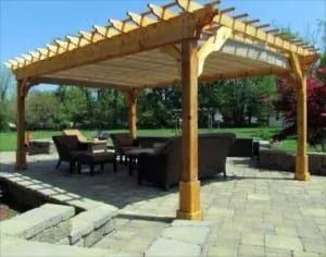Wooden pergola over patio with seating area.