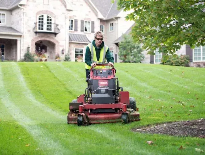 worker mowing a lawn with larger ride on mower 