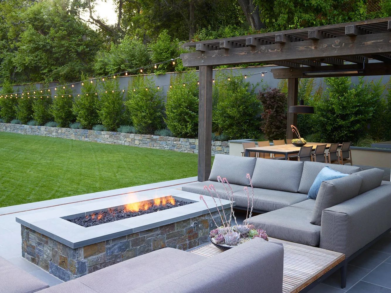 A patio with a fire pit and a sectional couch