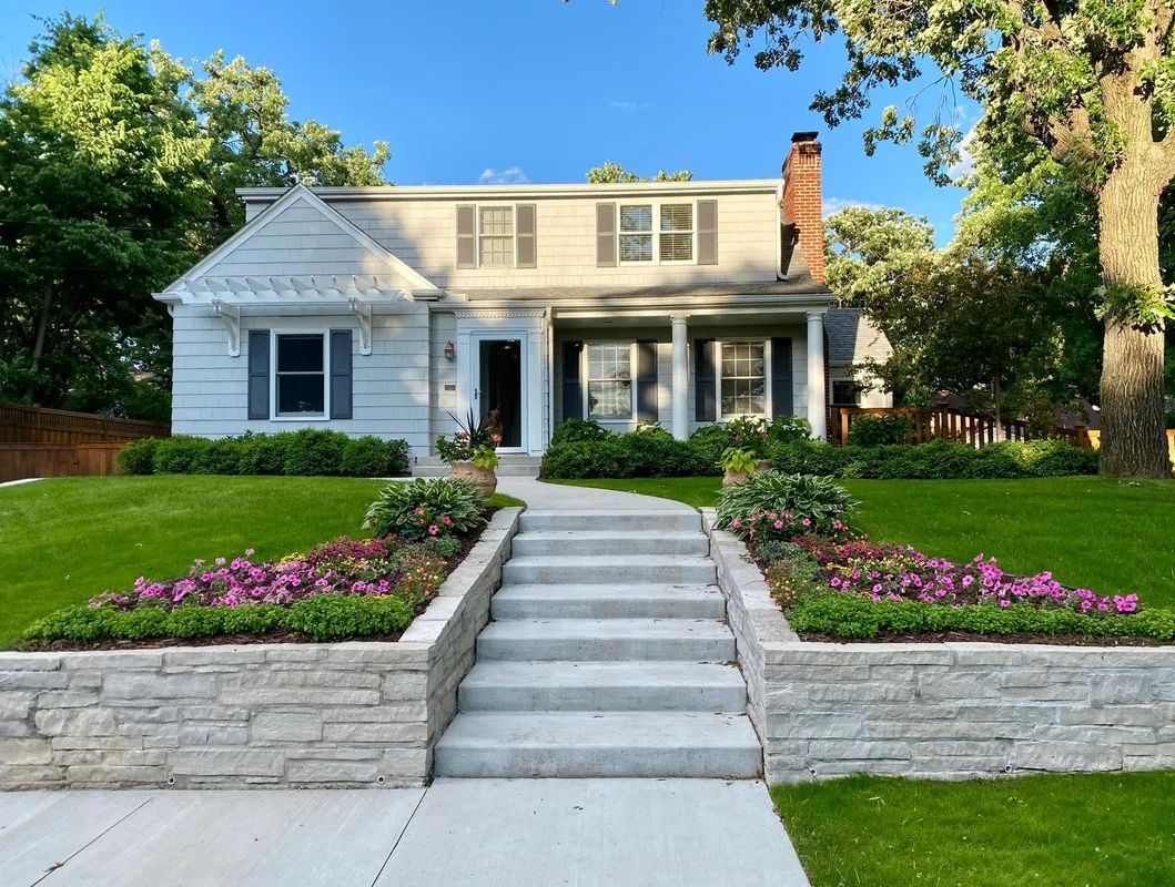 Front yard with nice stone retaining wall with wide front steps and colorful flowers 
