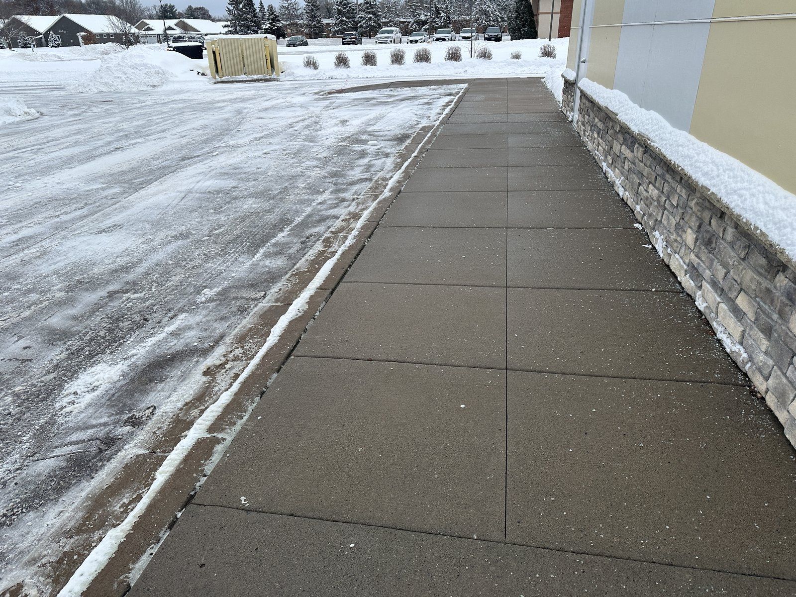 Cleared concrete walk running along the side of an office building after snow