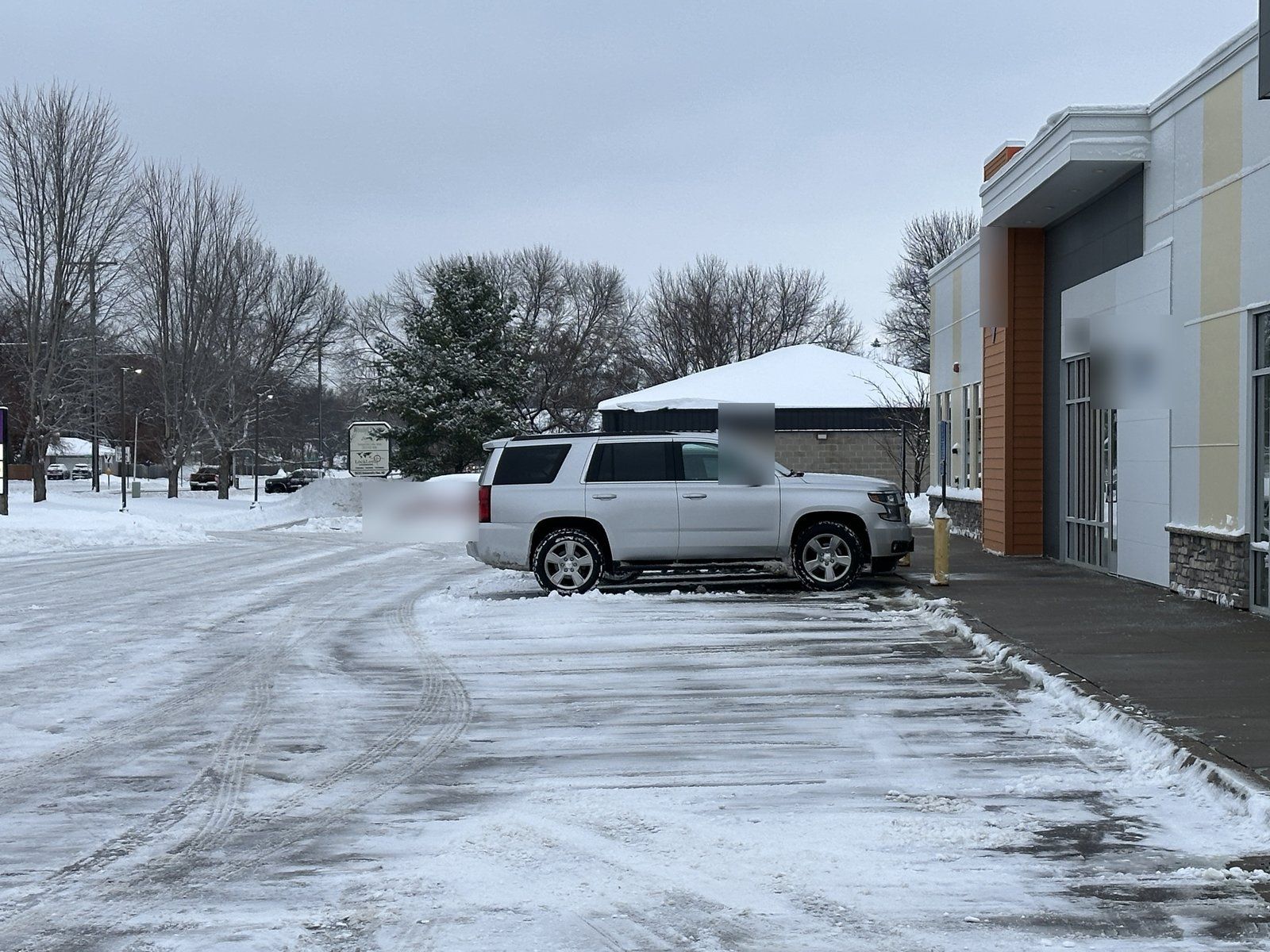 Plowed parking lot at an office building with an SUV parked near the entrance