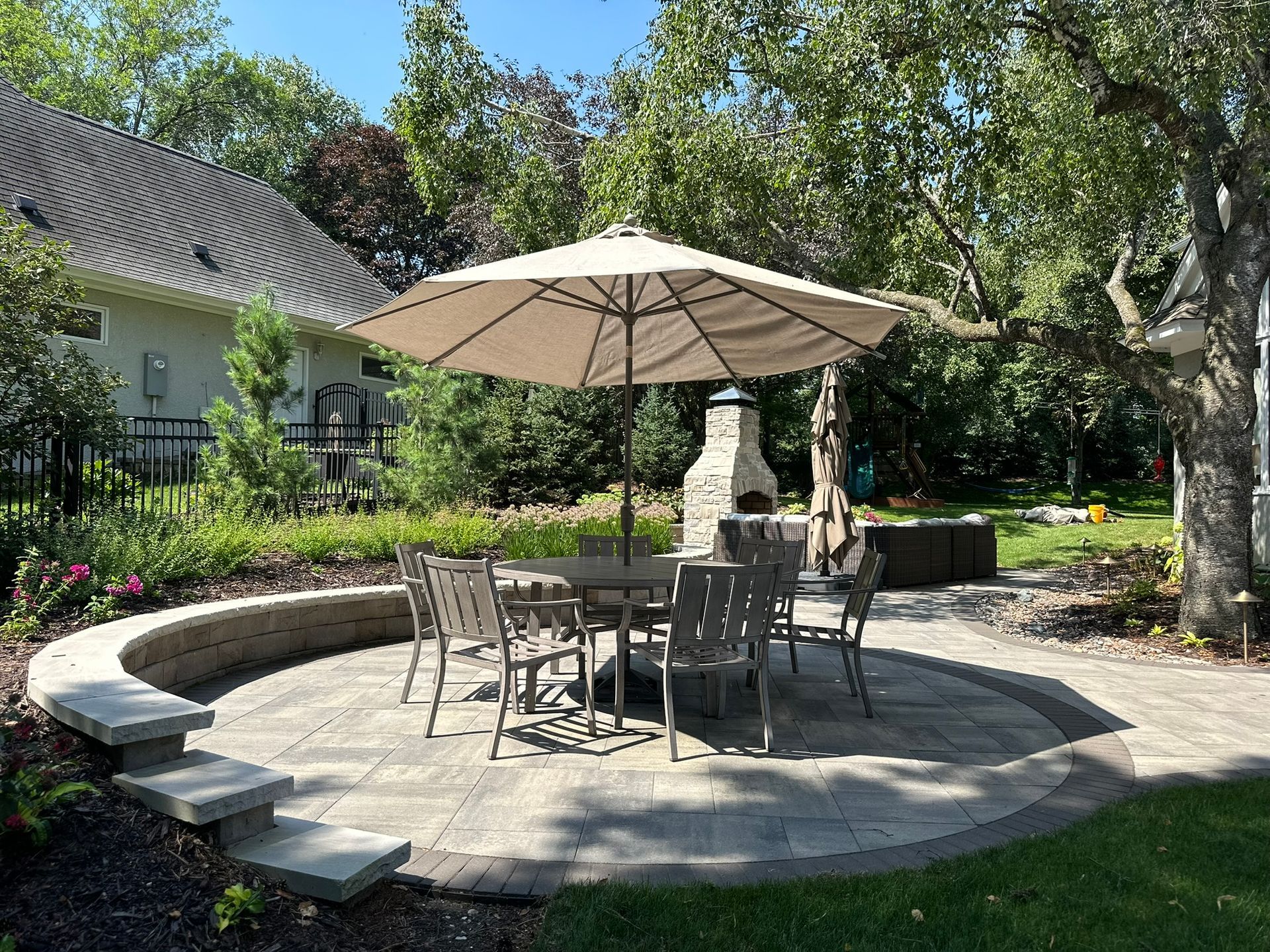 After: backyard patio with circular inlay section for a round dining table with large gray pavers in Minnetonka MN 