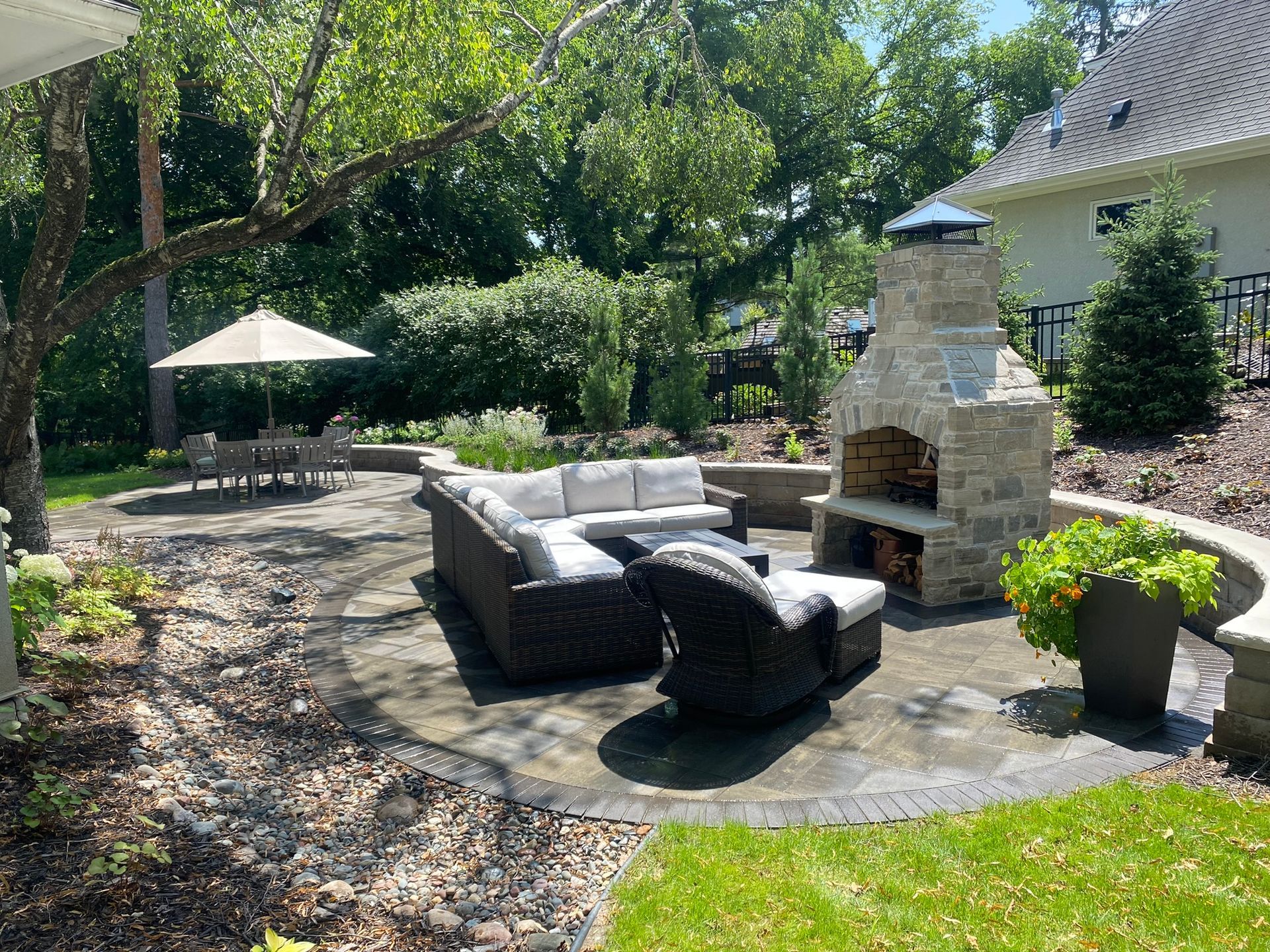 Minnetonka MN patio featuring a custom natural stone outdoor fireplace and wicker furniture