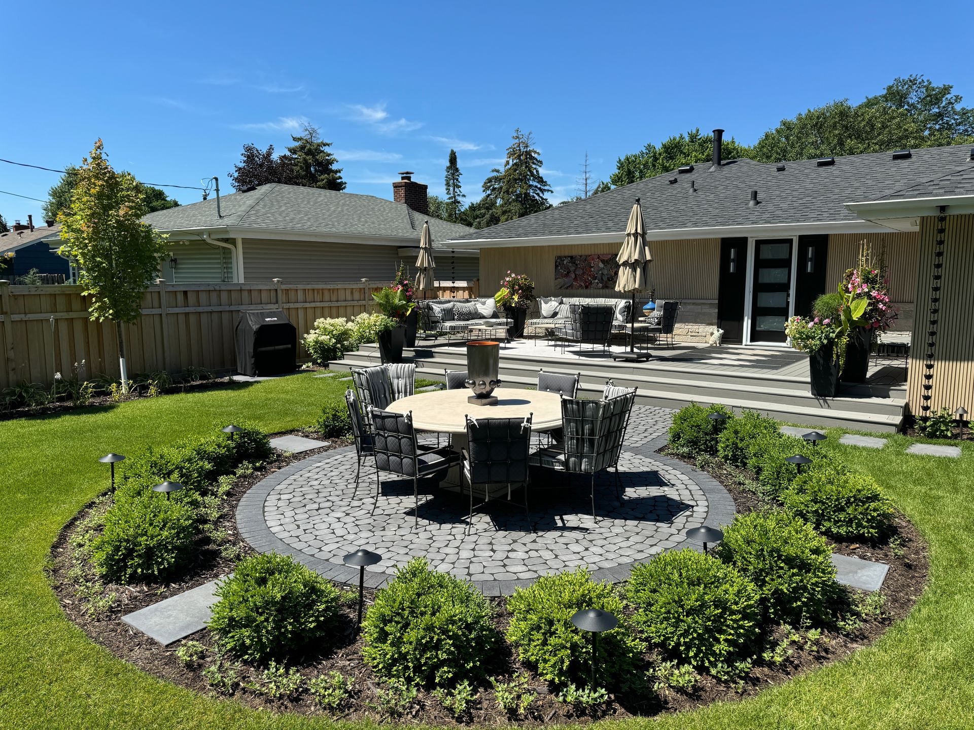 Edina MN backyard outdoor living space with lounge, dining table, grill, stepping stones, flower pots, and outdoor art