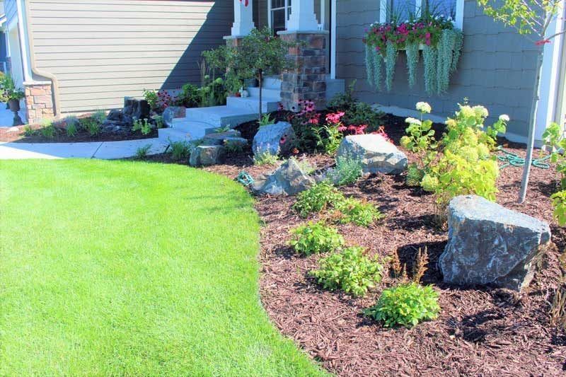 Front yard boulder outcropping with colorful flowers and a redbud tree in Chanhassen MN