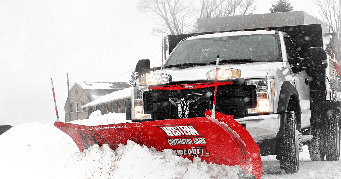 Snowplow truck plowing snow on a road in a winter setting.