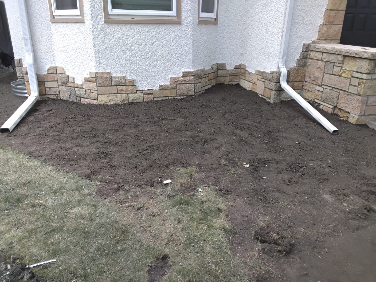 Prepared soil along a Minneapolis home foundation before sod installation