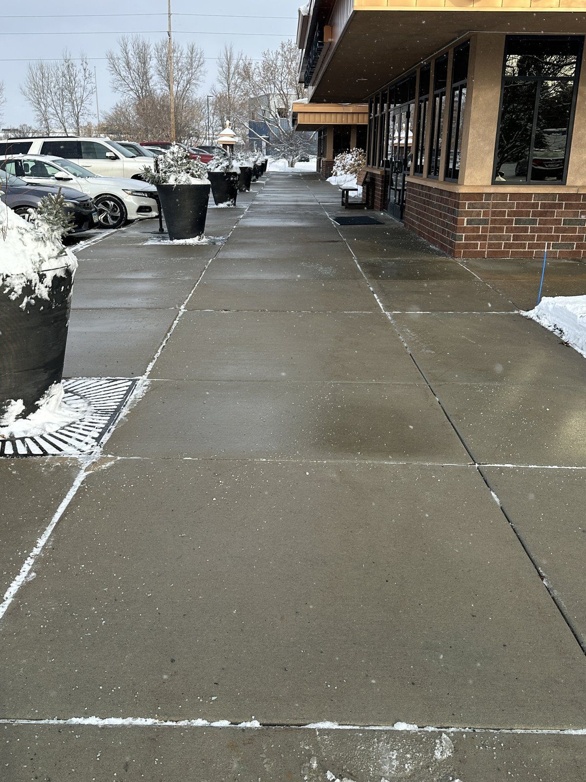 Commercial sidewalk shoveled and salted down to bare concrete beside a building
