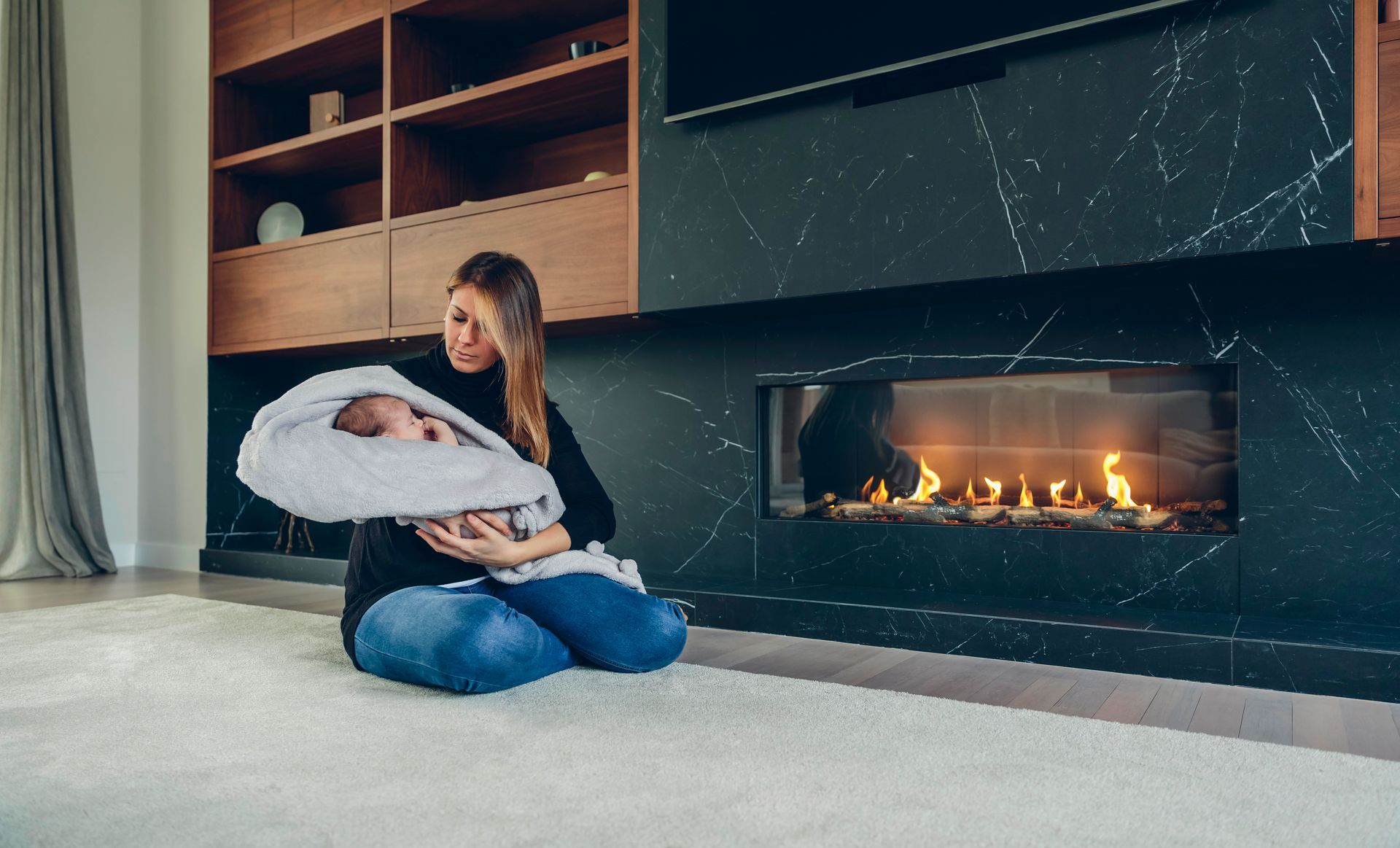 Fireplace with flames, set in a rectangular opening of a light wood paneled wall.