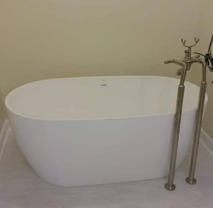 A white oval bathtub with a silver faucet in a bathroom.