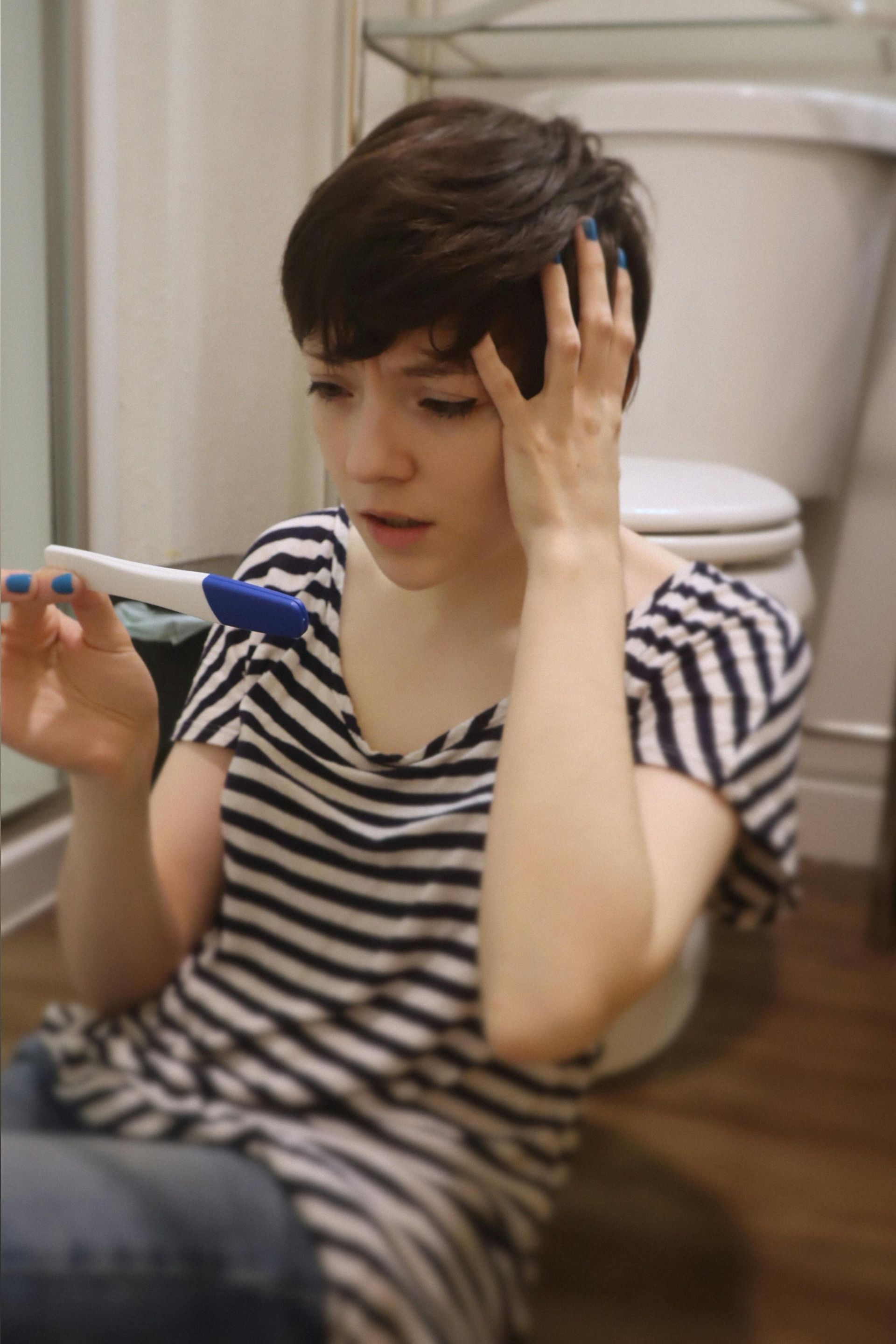 A woman sitting on the floor holding a pregnancy test
