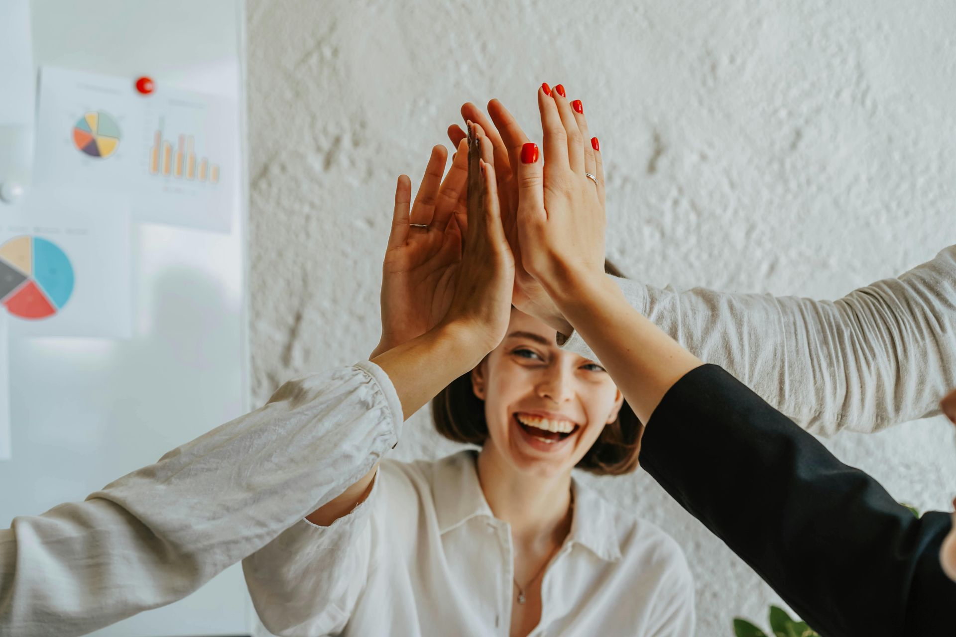 Group of women smiling and giving a high-five during a support meeting.