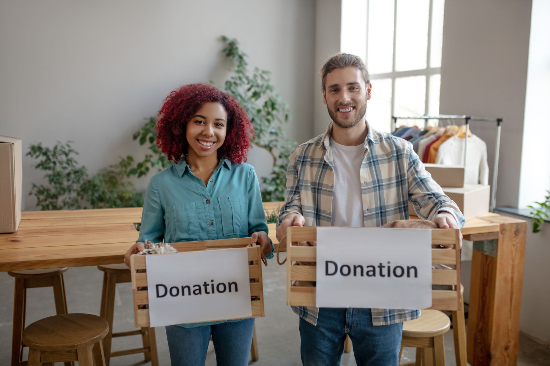 A man and a woman are holding wooden boxes with donation signs on them.