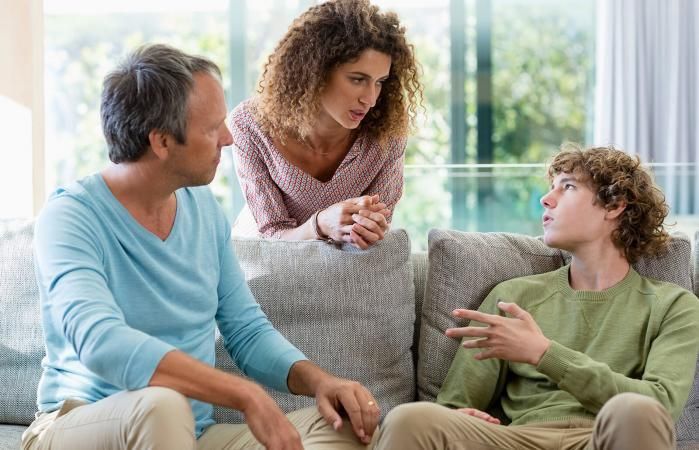 Family of three in living room, having a serious conversation.