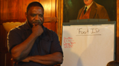 Man pondering, standing next to a whiteboard labeled 