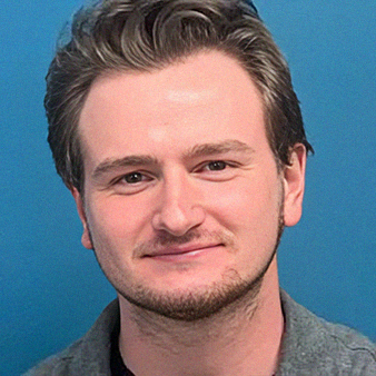 Young man with light skin, short brown hair, and a slight smile, against a blue background.