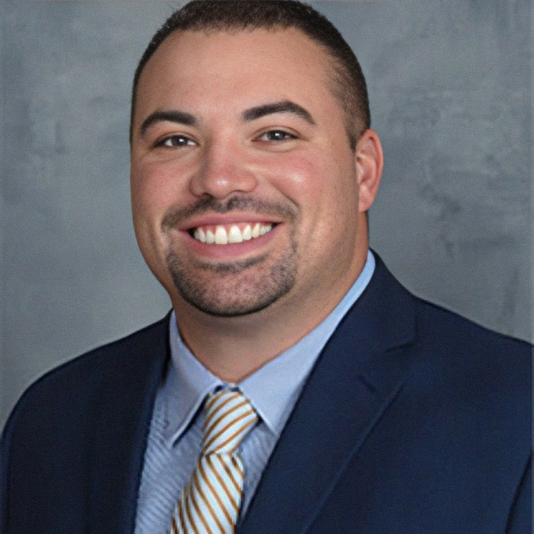 Man with a warm smile, wearing a blue suit, light blue shirt, and a gold-striped tie.