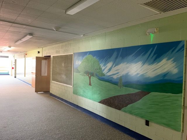 Hallway with artwork of a tree and path, next to a dark board.