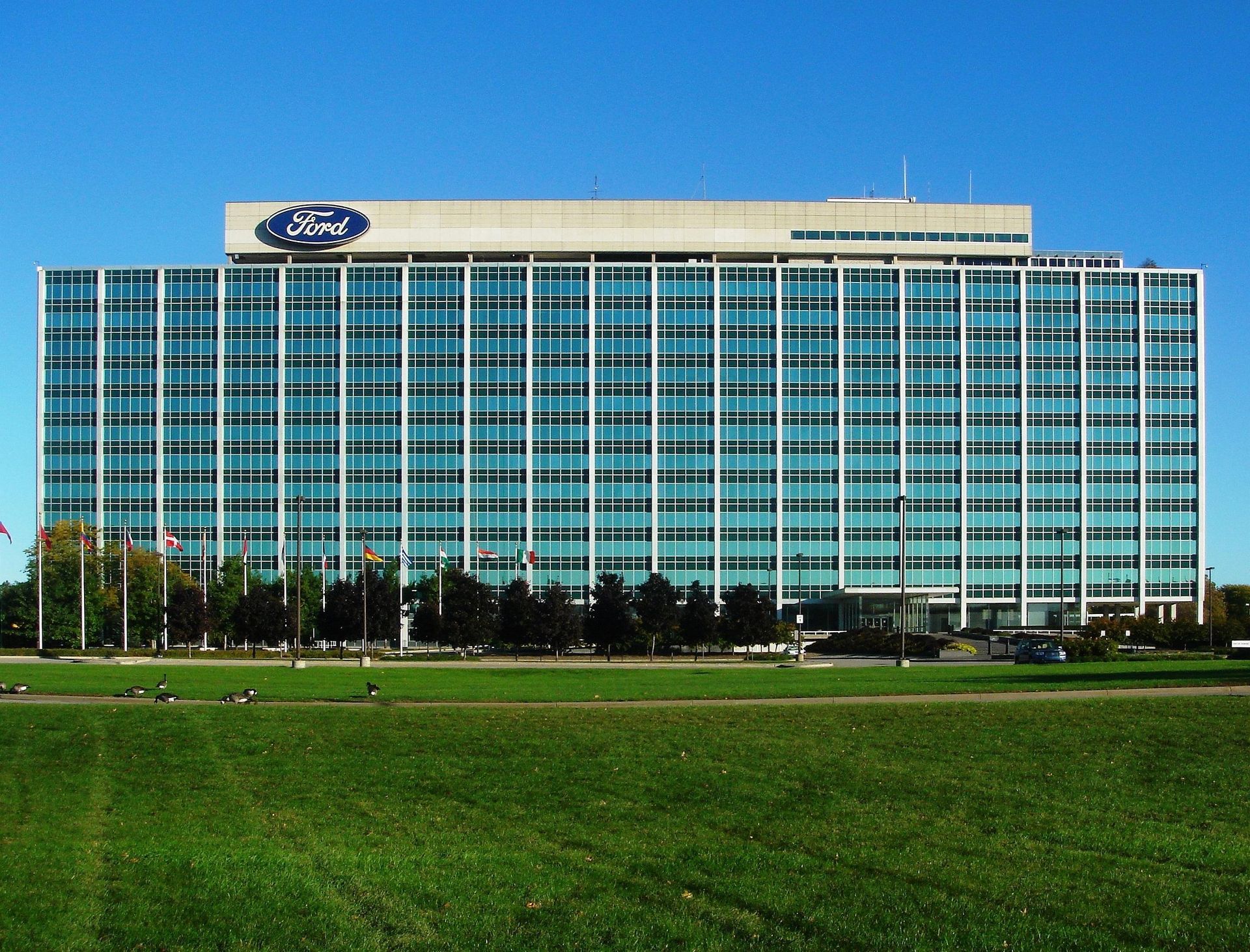 Ford World Headquarters, a large blue-tinted glass and white building, with the Ford logo on top.