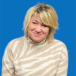 Blonde woman in zebra-print sweater smiles; blue backdrop.