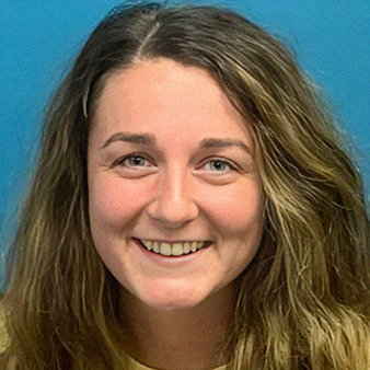 Woman with fair skin, smiling, light brown hair, against a blue backdrop.