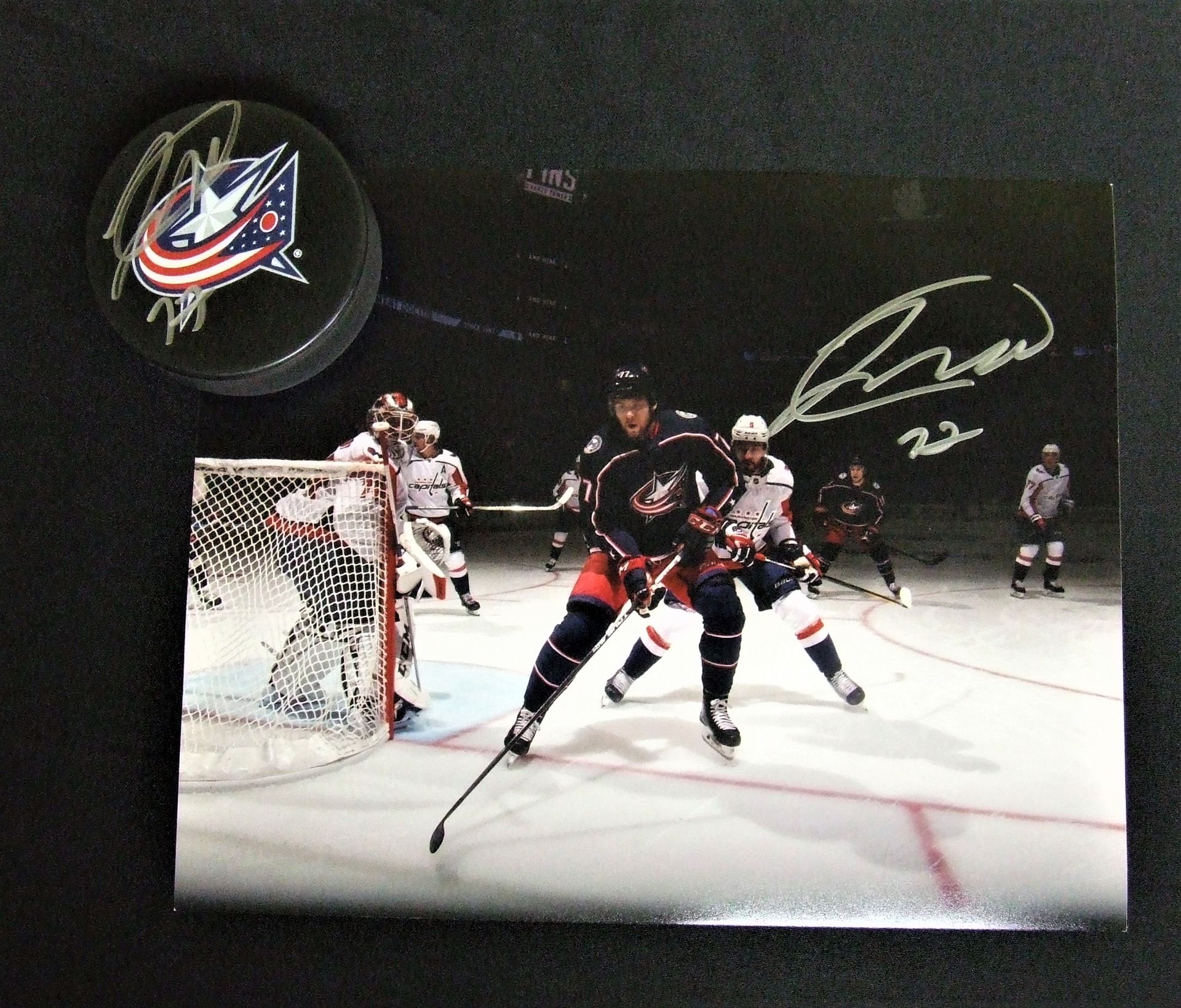 Autographed photo of a Columbus Blue Jackets player in action with an autographed hockey puck.